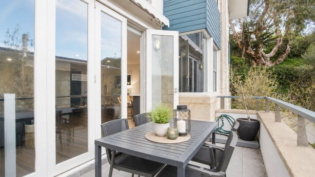 Un patio exterior con una mesa, sillas, una planta en maceta y un farol.