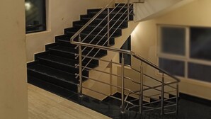 Un interior moderno con una escalera que tiene barandillas de metal y peldaños negros, que sube a un nivel superior.