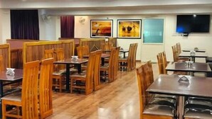 Un restaurante con mesasillas y cabinas de madera, un televisor de pantalla plana en la pared y obras de arte decorando las paredes.