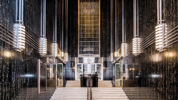 A grand lobby with marble walls, a central staircase, and a large clock. - Contemporary 2bed in Art Deco Heritage Site Elevea (Cape Town)
