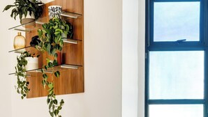 A modern living room with a white sofa, a coffee table, and a large window with a city view. - Contemporary 2bed in Art Deco Heritage Site Elevea (Cape Town)