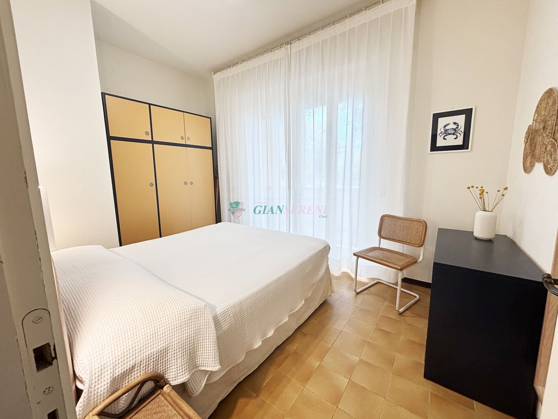 A bedroom with a bed, a chair, a desk, and a wardrobe.