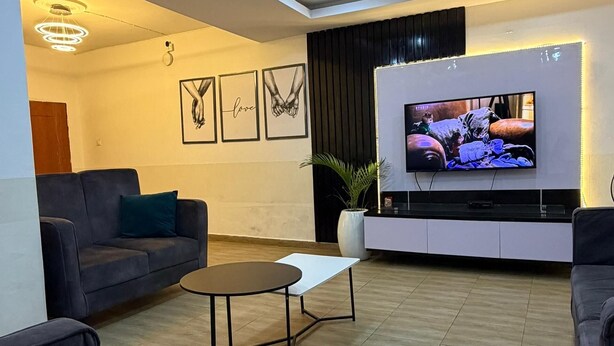 Un saló modern amb un sofà, una taula de centre, un televisor i obra d'art emmarcada a la paret.