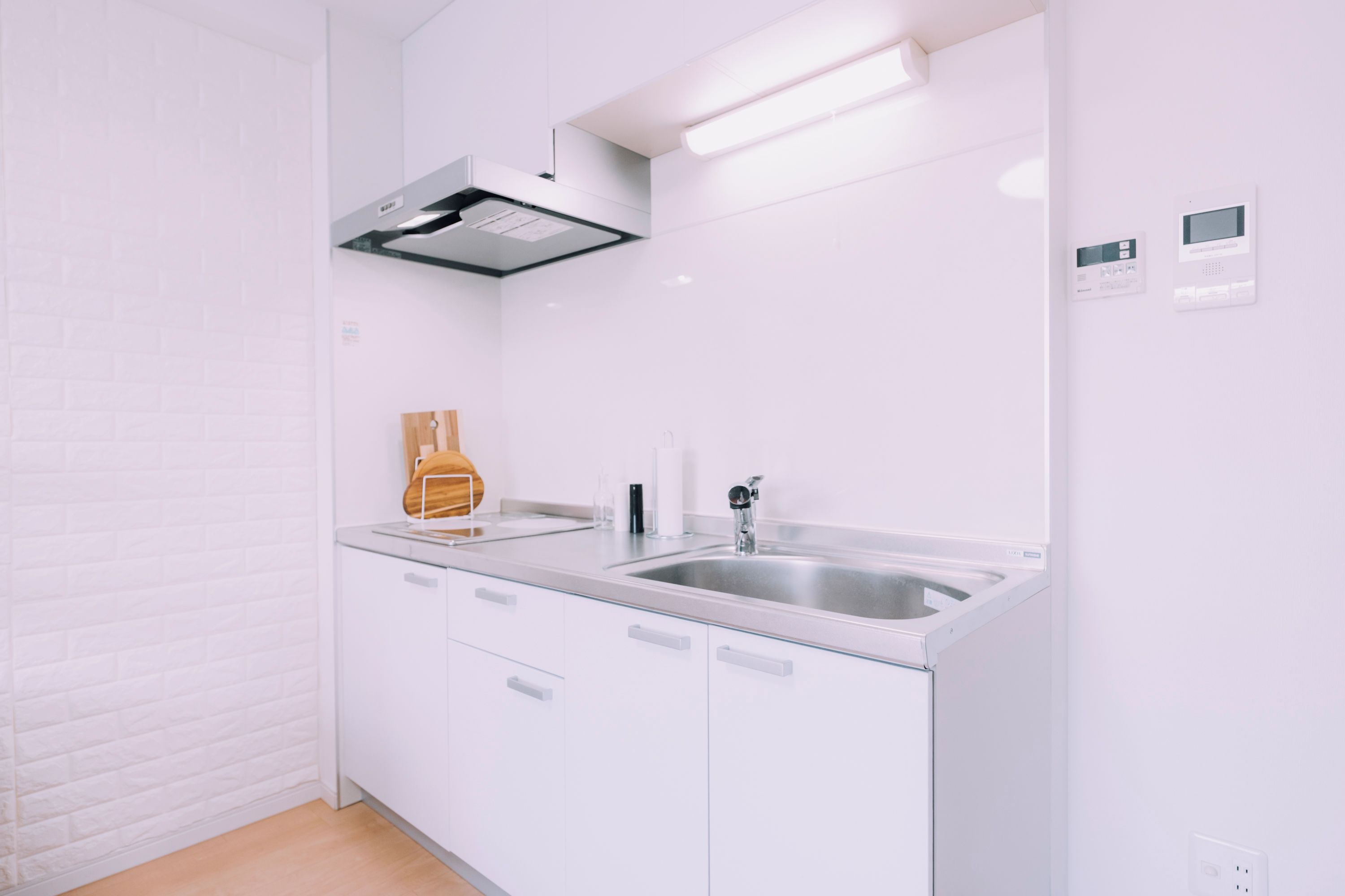 A modern kitchen with white cabinetry, stainless steel appliances, and a built-in oven.