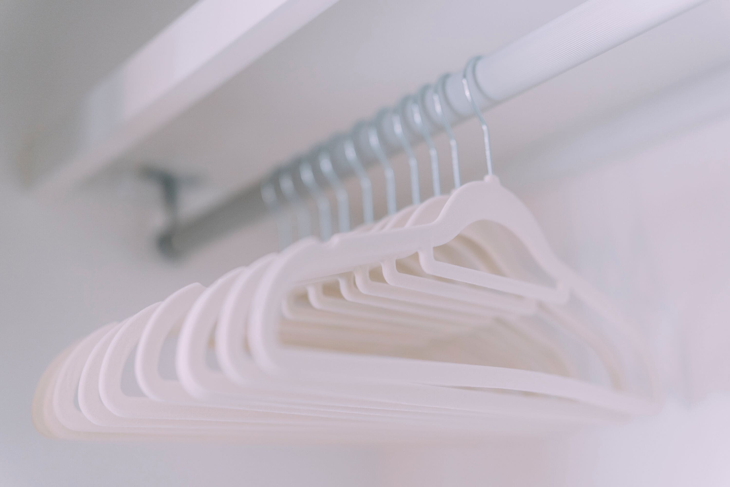 A white closet with a metal rod and plastic hangers.