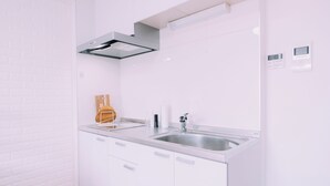 Eine moderne Küche mit weißen Schränken, Edelstahlarbeitsplatten, einem eingebauten Ofen und einer digitalen Bedienkonsole an der Wand.