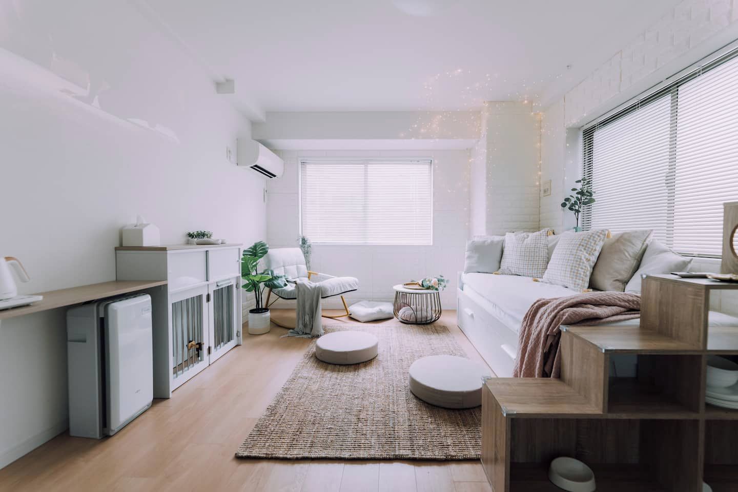A modern, well-lit room with a bed, seating area, and a small kitchenette.