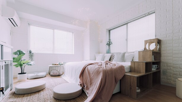 Ein Schlafzimmer mit Bett, Nachttischen, einer Pflanze und einem Fenster.