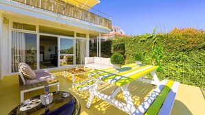 Un espacio exterior moderno con sofá, sillones y una tumbona.