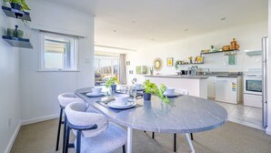Una cocina moderna con comedor, que incluye una mesa de mármol, sillas y vistas al exterior.