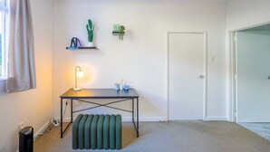 Una habitación con escritorio, lámpara, cactus y una puerta.