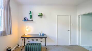 A room with a desk, a lamp, a cactus, and a door.