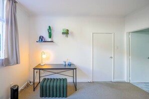 A room with a desk, a lamp, a cactus, and a door. - Charming 1-Bedroom Home in Prestigious Orakei (Auckland)