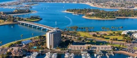 Un puerto deportivo con numerosas embarcaciones amarradas, un puente y un edificio grande de diseño moderno.