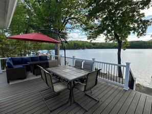 A deck with a table and chairs, a red umbrella, and a blue sofa. - Glass Lake Cottage (Averill Park)