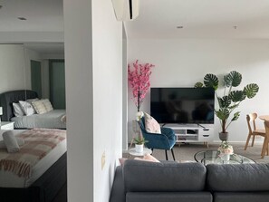 A modern living room with a sofa, a TV, a coffee table, and decorative plants.