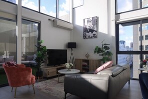 Ett modernt vardagsrum med en platt-TV, en soffa i läder och ett stort fönster med utsikt över staden.