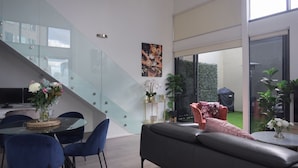 A modern living space with a staircase, dining area, and a view of a garden. - Rare Loft Style Penthouse Bourke St Mall + Parking (Melbourne)