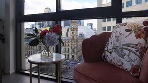 A room with a view of a historic building, a vase with flowers, and a floral pillow. - Rare Loft Style Penthouse Bourke St Mall + Parking (Melbourne)