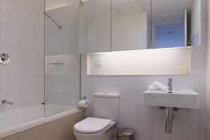Ett badrum med en dusch som är avskärmad med glasväggar, en toalett, ett handfat och en spegel.