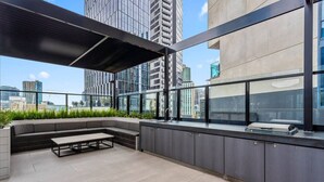 Una terrazza sul tetto con angolo salotto, tavolo e vista sulla città.