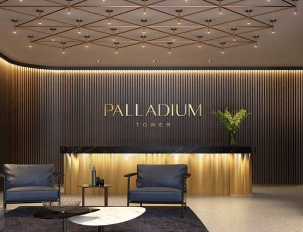 A reception area with a modern design, featuring a reception desk, two seating areas, and a geometric ceiling pattern.