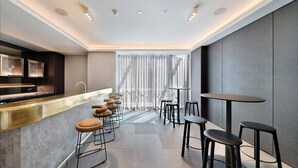 Un'area bar moderna con un bancone, sgabelli e tavoli.