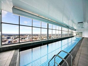 Una piscina interior amb vistes a la ciutat, grans finestres i un disseny modern.
