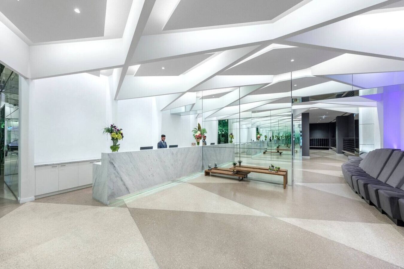 A modern reception area with a marble counter, seating, and glass walls.