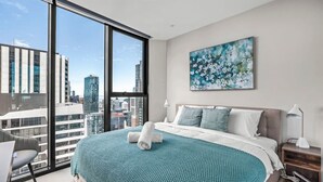 Een moderne hotelkamer met een groot bed, uitzicht over de stad en een schilderij aan de muur.