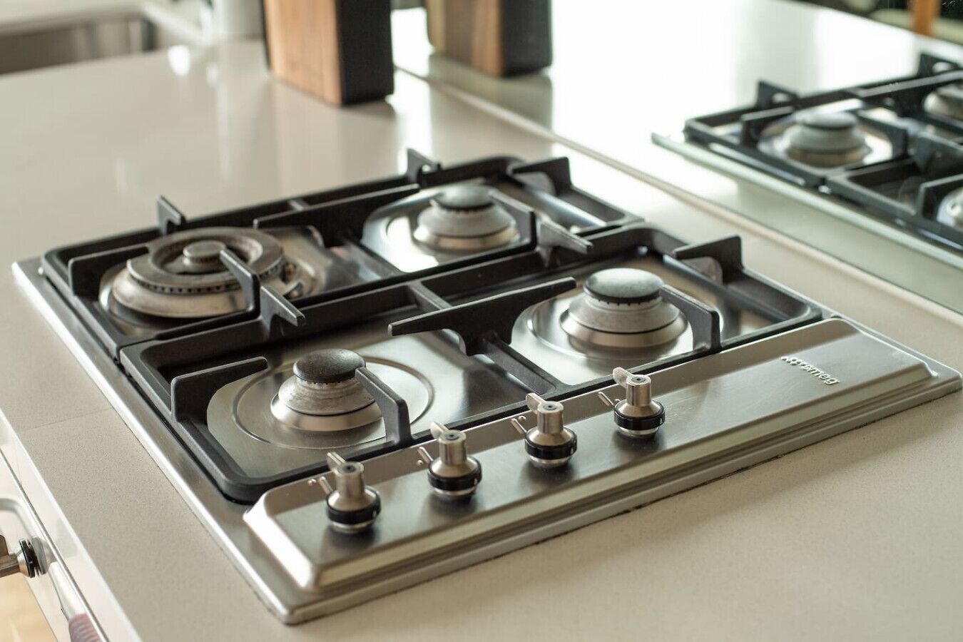 Une cuisine équipée d’une cuisinière à gaz, de quatre brûleurs et d’une hotte aspirante.
