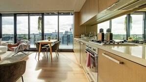 Ett modernt kök med stora fönster, en matplats och utsikt över stadsbilden.