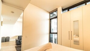 Une chambre d’hôtel moderne, équipée d’un lit, d’une grande fenêtre et d’une armoire.