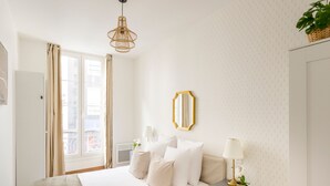 A bedroom with a bed, bedside tables, a mirror, and a window with curtains. - Family Suites Caumartin I-II (Paris)