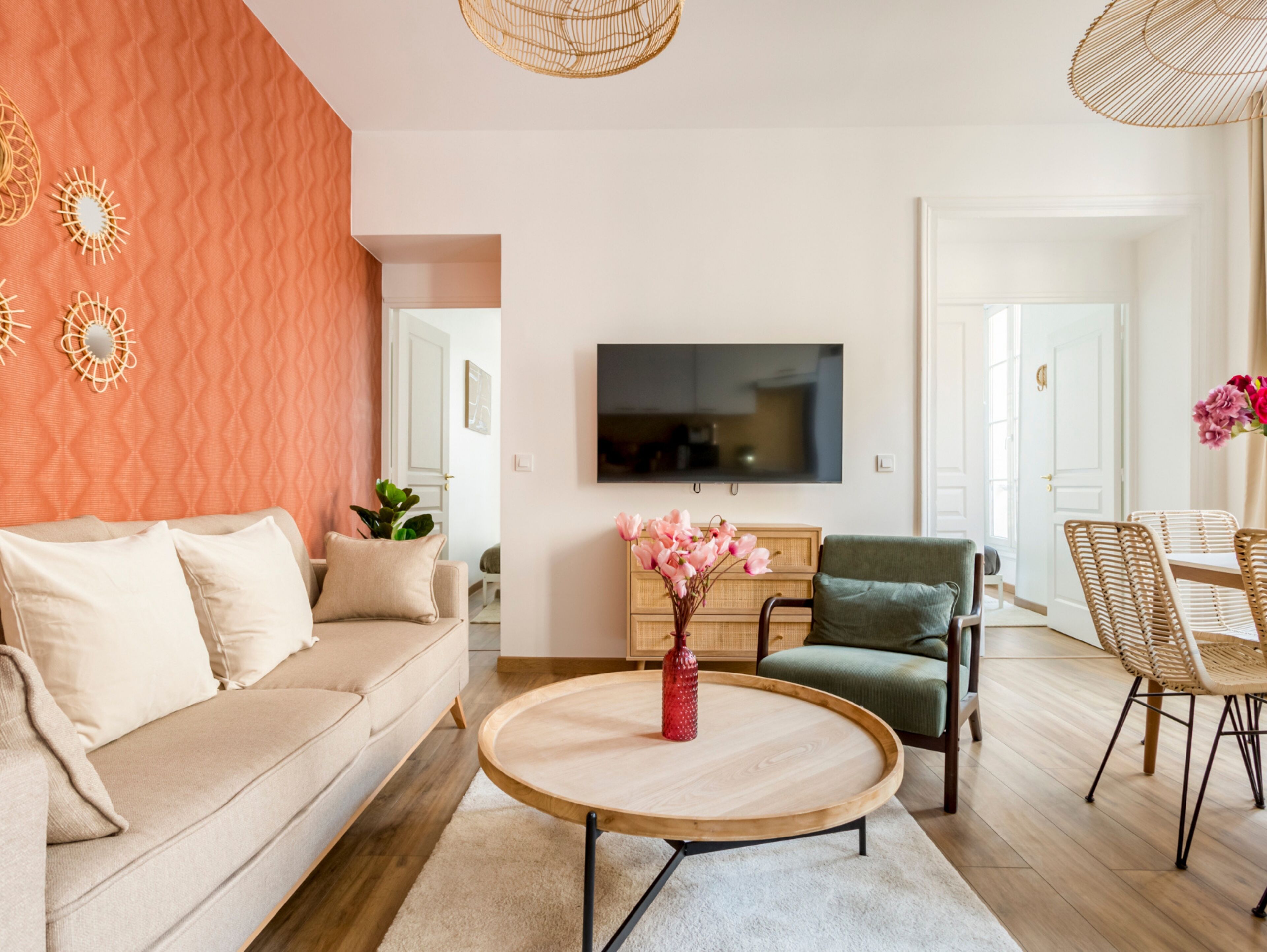 Una sala de estar moderna con sofá, una mesa de centro, televisor y un comedor con sillas.