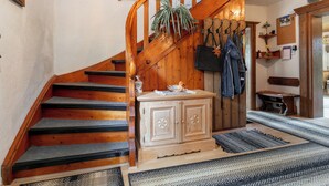Eine Holztreppe mit Handlauf, eine Holzkommode und ein Kleiderhaken mit aufgehängter Kleidung.