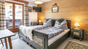Ein Schlafzimmer mit Holzwand, einem Bett mit gestreifter Bettwäsche, einer Chandelüster, einem Fernseher und einem kleinen Tisch.