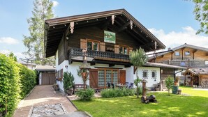 Ein traditionelles Chalet mit Holzbalkon, einem Steinweg und einem gepflegten Garten.