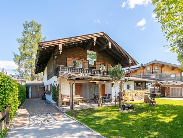 A traditional wooden chalet with a balcony, stone pathway, and a well-maintained garden.
