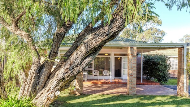 A covered outdoor area with a brick column, a glass door, and a white chair. - Emu Point Beach Cottages (Emu Point)