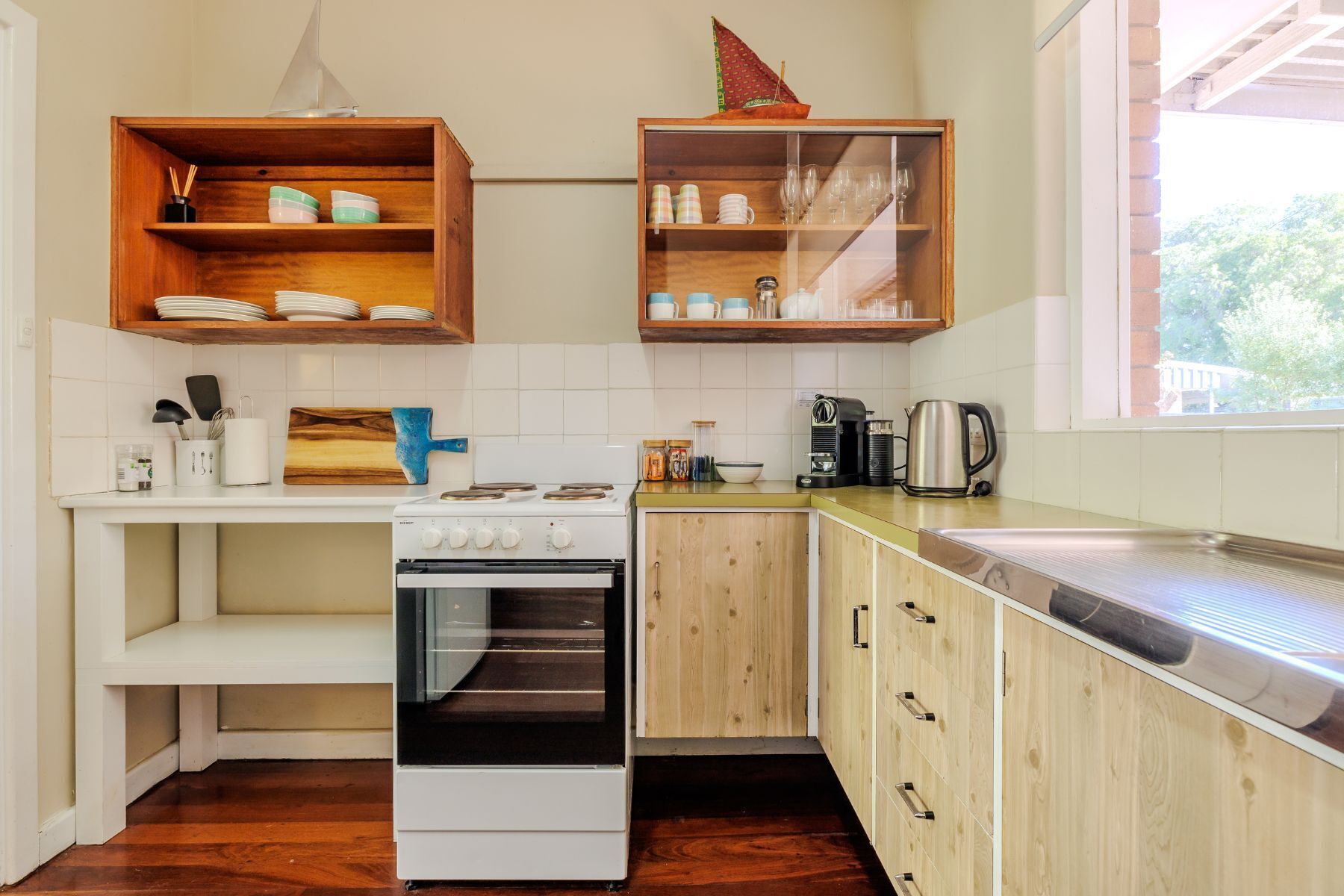 Una cocina con armarios de madera, una estufa blanca y un ventanal que proporciona luz natural.