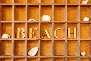 Wooden letters spelling "BEACH" with small seashells scattered around. - Emu Point Beach Cottages (Emu Point)