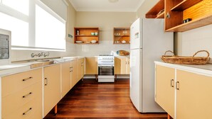 A kitchen with wooden cabinets, a stove, and a refrigerator. - Emu Point Beach Cottages (Emu Point)
