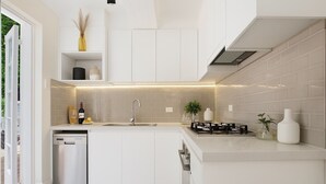 Une cuisine moderne avec des meubles blancs, un lave-vaisselle encastré, une cuisinière à gaz et un petit espace de comptoir agrémenté d’objets décoratifs.