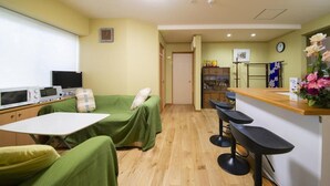 A compact hotel room with a kitchenette, a single bed, a small table, and a bar area with stools. - Shukubou Shinsen (Kanazawa)