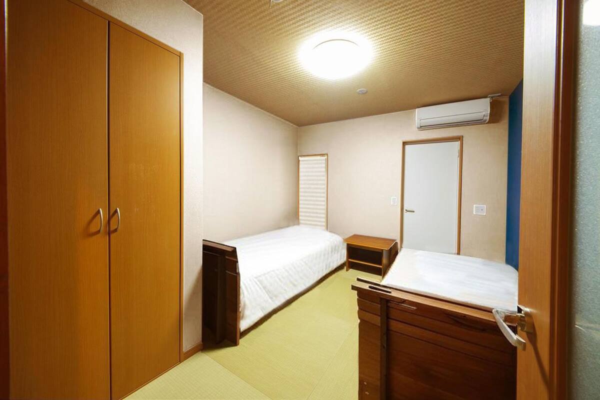 A small, compact room with a single bed, a wardrobe, and a desk.