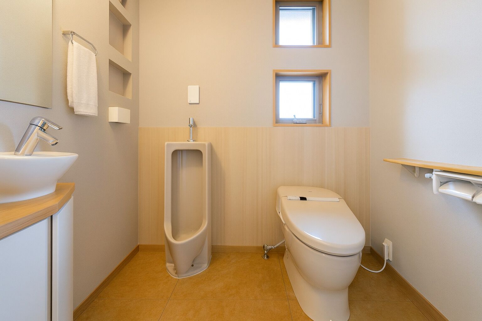 A small, clean bathroom with a urinal, toilet, sink, and a mirror.