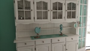 A white wooden cabinet with glass doors and two decorative seahorses on a green placemat.