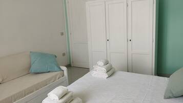 A bedroom with a bed, a sofa, and a wardrobe.