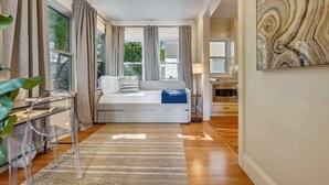 A bedroom with a bed, a desk, a lamp, and a painting.